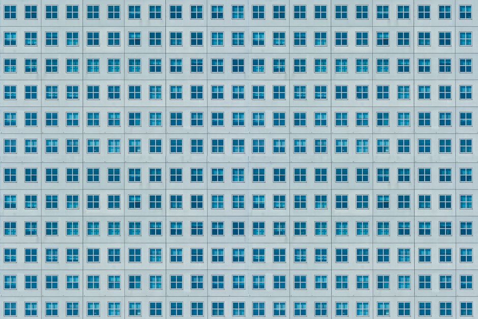 Facade of a modern building with symmetrical, repetitive window patterns creating an urban texture.